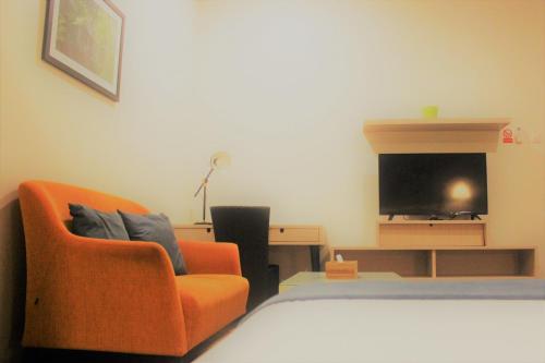 a bedroom with an orange chair and a television at Treehouse Suites - Boutique Serviced Apartment in Jakarta