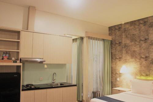 a bedroom with a bed and a kitchen with a sink at Treehouse Suites - Boutique Serviced Apartment in Jakarta