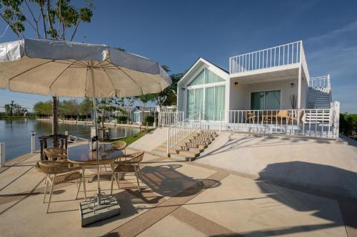 uma casa com um pátio com uma mesa e um guarda-chuva em Saksiam Lakeside Resort SHA PLUS Certificate em Nonthaburi