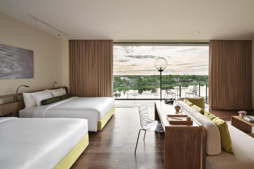 um quarto de hotel com duas camas e uma grande janela em neera retreat hotel em Nakhon Pathom