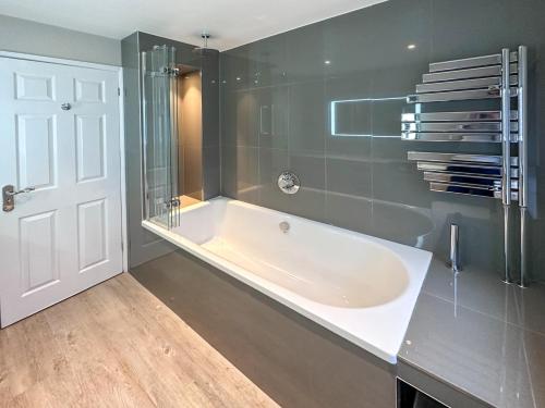 bagno con vasca e doccia in vetro di BLUNSDON LODGE - Spacious Bungalow, High Speed Wi-Fi, Free Private Parking, Garden a Swindon