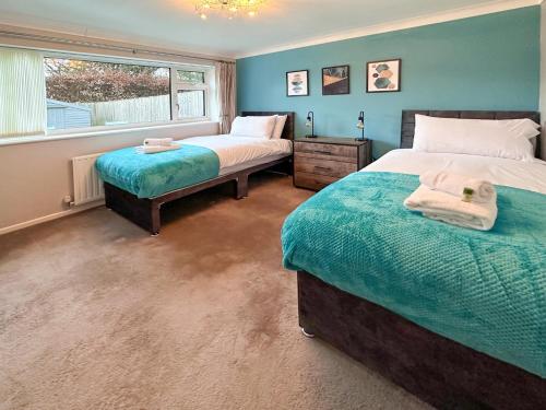 1 dormitorio con 2 camas y ventana en BLUNSDON LODGE - Spacious Bungalow, High Speed Wi-Fi, Free Private Parking, Garden, en Swindon