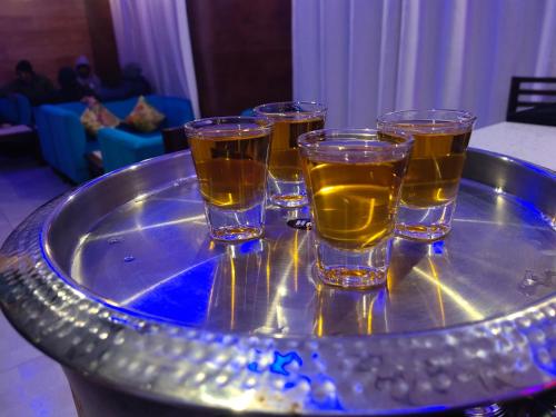 a tray with four glasses of beer on a table at Satopanth The Auli Resort By Royal Collection Hotels in Joshīmath