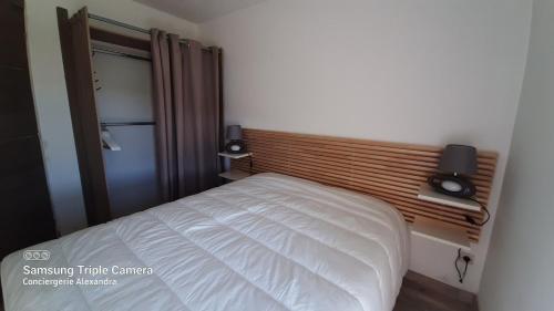Schlafzimmer mit einem weißen Bett mit einem Kopfteil aus Holz in der Unterkunft LES GOELLETTES : vue mer et piscine in Saint-Cyprien
