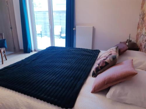 a bed with a blue blanket on top of it at B&B Caprice d'Epices in Francorchamps