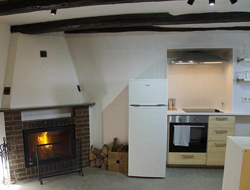 a kitchen with a white refrigerator and a fireplace at Cal Moliner De Castelladral in Castelladral