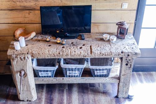 a wooden table with baskets on it with a television on it at La cabane du cerf et son sauna in Attre