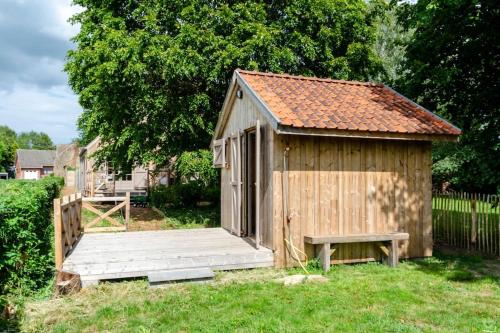a small wooden shed with a bench in a yard at La cabane du cerf et son sauna in Attre