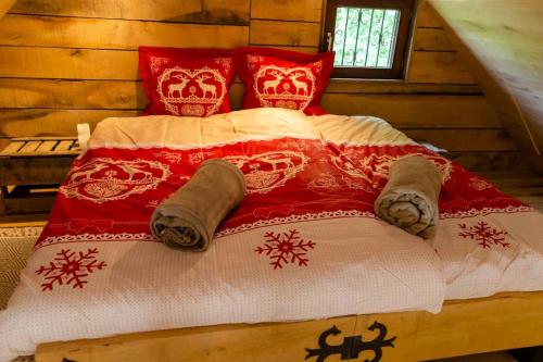uma cama com um cobertor e almofadas vermelhos e brancos em La cabane du cerf et son sauna em Attre