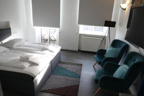 a bedroom with a bed and two blue chairs at Art Hotel Charlottenburger Hof Berlin in Berlin