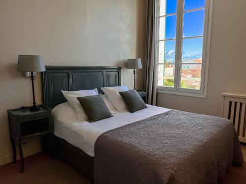 a bedroom with a bed with pillows and a window at Le Chat Botté in Saint-Clément-des-Baleines