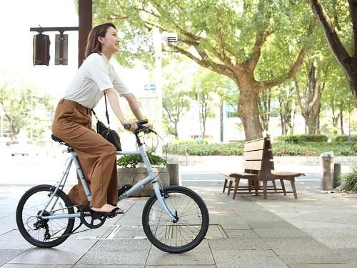 a woman riding a bike on a sidewalk at UAN kanazawa in Kanazawa