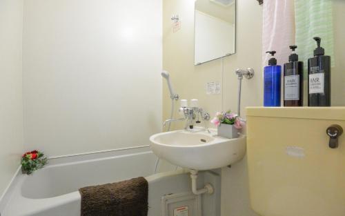 a white bathroom with a sink and a bath tub at Carid Shiraishi In front of the station / Vacation STAY 4651 in Sapporo