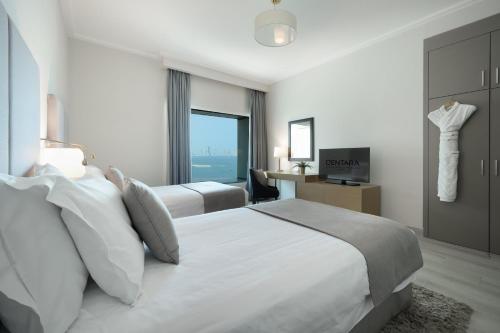 a hotel room with two beds and a television at Centara West Bay Hotel & Residences Doha in Doha