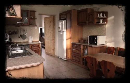 a kitchen with wooden cabinets and a white refrigerator at Dwór Jeziory Wielkie in Jeziory Wielkie