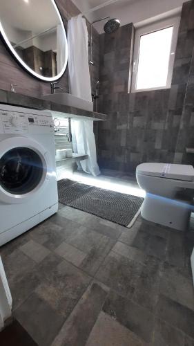 uma casa de banho com uma máquina de lavar roupa e um WC em Glyfada Vacation Apt em Atenas