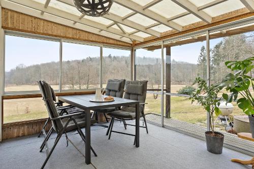 a dining room with a table and chairs and windows at Villa Ulvatorp nära Varberg och Ullared in Veddige