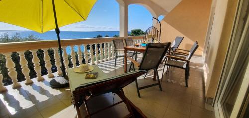 balcón con mesa, sillas y sombrilla en Comfortable family apt Iris 20m from beach in Mandre, en Mandre
