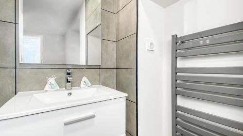 La salle de bains est pourvue d'un lavabo blanc et d'un miroir. dans l'établissement HOMEY FRIENDLY - Proche Gare - Terrasse privée - Wifi, à La Roche-sur-Foron