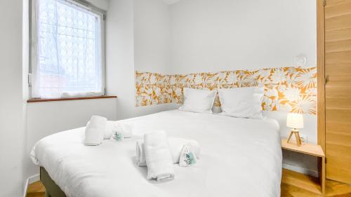 a bedroom with a large white bed with towels on it at HOMEY FRIENDLY - Proche Gare - Terrasse privée - Wifi in La Roche-sur-Foron