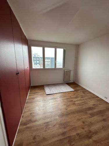 ein leeres Zimmer mit Holzböden und zwei Fenstern in der Unterkunft Étoile en banlieue parisienne in Montigny-lès-Cormeilles