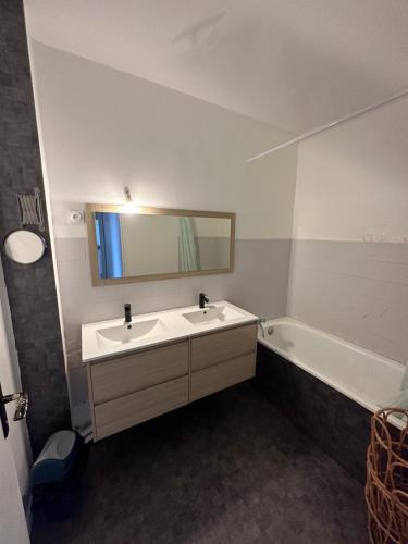 ein Badezimmer mit einem Waschbecken, einem Spiegel und einer Badewanne in der Unterkunft Étoile en banlieue parisienne in Montigny-lès-Cormeilles