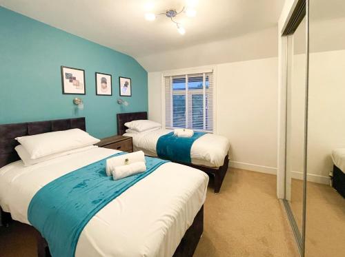 two beds in a room with blue walls at SHRIVENHAM - Spacious Home, High Speed Wi-Fi, Free Parking, Garden in Swindon