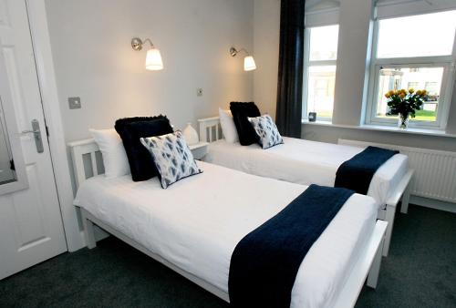 two beds in a room with two windows at The Sliding Rock Inn in Galway