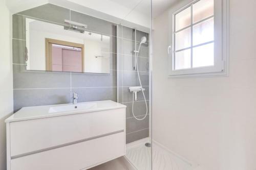 a white bathroom with a sink and a mirror at PETIT CORAIL Duplex agreable St Raphael - proche mer in Saint-Raphaël