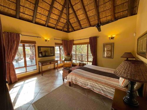 a bedroom with a large bed and a balcony at Lodge on Watering Hole , Zebula in Mabula