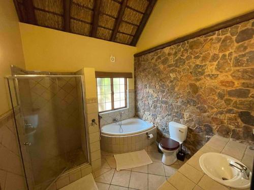 a bathroom with a tub and a toilet and a sink at Lodge on Watering Hole , Zebula in Mabula