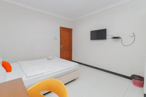 Habitación con cama y TV en la pared. en KoolKost near Tunjungan Plaza en Surabaya