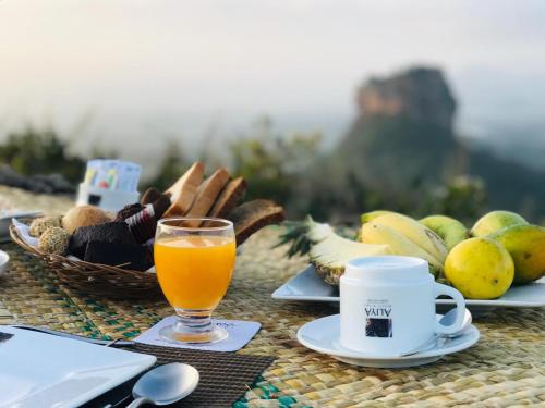 a table with a glass of orange juice and a basket of fruit at Aliya Resort and Spa - Thema Collection in Sigiriya