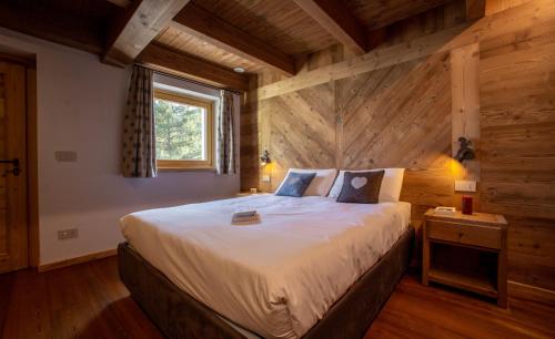 a large bed in a room with a wooden wall at Fleur des neiges & Spa - Adults only in Ayas