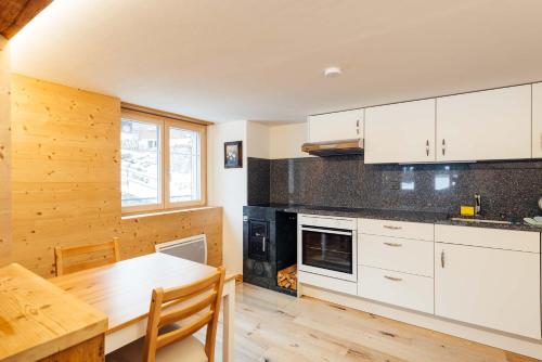 uma cozinha com armários brancos e uma mesa de madeira em Casa Nacla Sedrun/Surrein em Sedrun