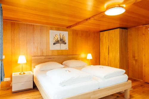 a bedroom with a large white bed with wooden walls at Casa Nacla Sedrun/Surrein in Sedrun