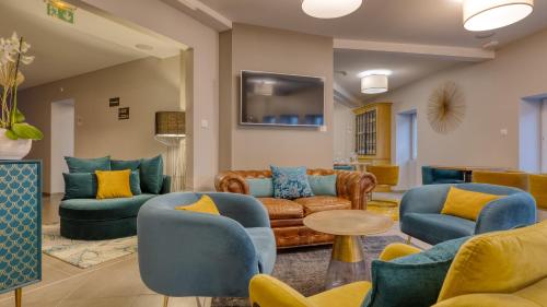 salon z kanapami i krzesłami oraz telewizorem w obiekcie Hôtel L'Orée des plages w mieście Clohars-Carnoët