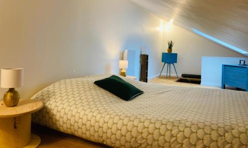 a bedroom with a large bed with a green pillow at Charmante petite maison rénovée in Quistinic