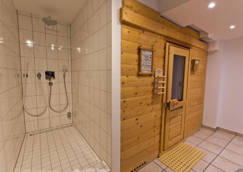 baño con ducha y puerta de madera en Astor & Aparthotel, en Colonia