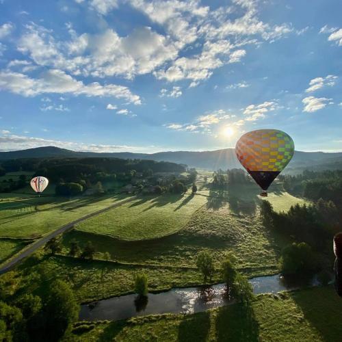 two hot air balloons are flying over a field at L'ancien Relais de Poste*** in Saint-Dier-dʼAuvergne