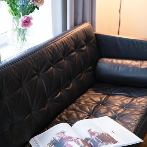 a brown leather couch with two books on it at TwentySix in Malmö