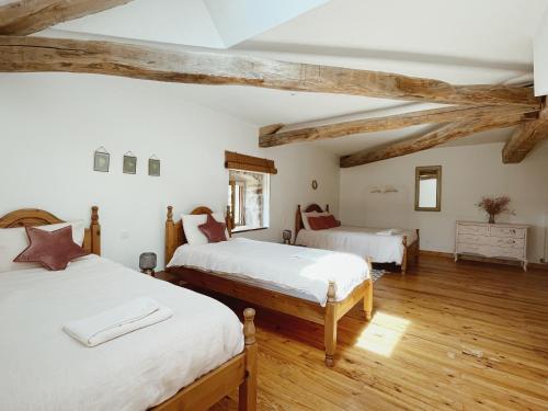 Duas camas num quarto com vigas de madeira em L'ancien Relais de Poste*** em Saint-Dier-dʼAuvergne