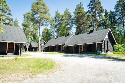 a row of black barns with trees in the background at Break Sokos Hotel Bomba in Nurmes
