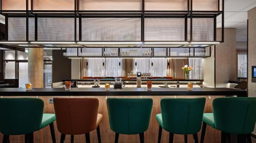 a restaurant with a bar with green chairs at Hey Lou Hotel Karlsruhe Messe in Karlsruhe