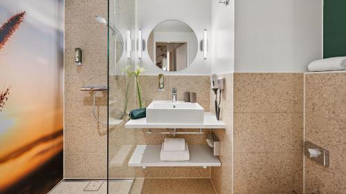 ein Bad mit einem Waschbecken und einer Dusche in der Unterkunft Styles Hotel Karlsruhe Messe in Karlsruhe