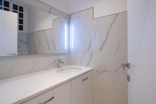 La salle de bains blanche est pourvue d'un lavabo et d'un miroir. dans l'établissement Sea view, vue sur la mer Port De Nice - Appartement de charme 2 P, à Nice