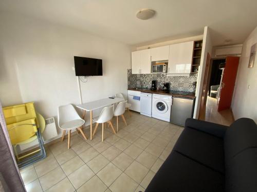une cuisine avec une table et des chaises dans une pièce dans l'établissement Sol-y-Days Goeland, Appartement avec terrasse front de mer et place de parking en centre-ville, au Grau-du-Roi