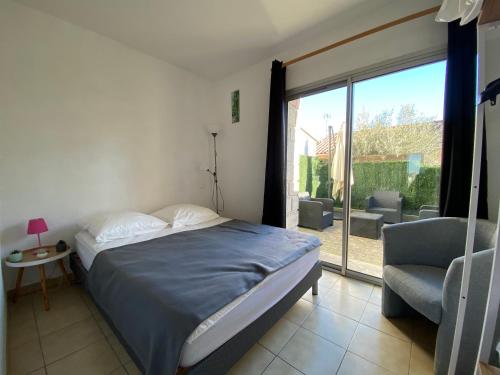 une chambre avec un lit, une chaise et une fenêtre dans l'établissement Sol-y-Days Goeland, Appartement avec terrasse front de mer et place de parking en centre-ville, au Grau-du-Roi