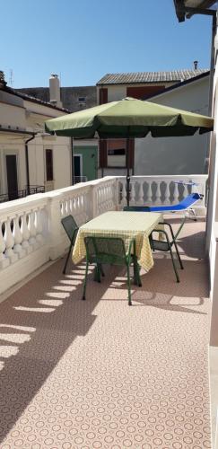 stół i zielony parasol na balkonie w obiekcie Civico 27 - In Terrazza w mieście Casalbordino