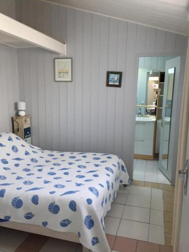 um quarto com uma cama com um edredão azul e branco em Petite maison dans le jardin em Ars-en-Ré